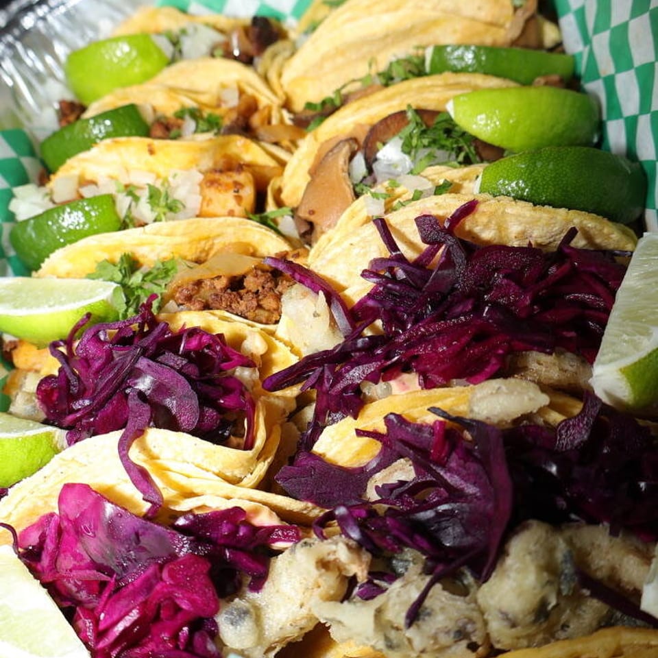 Catering tray of tacos with lime wedges